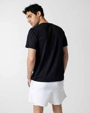 Man wearing a black t-shirt and white shorts on a plain background