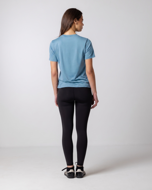 Person wearing a blue t-shirt and black leggings on a white background