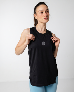 Woman wearing a black sleeveless top and light blue leggings on a white background