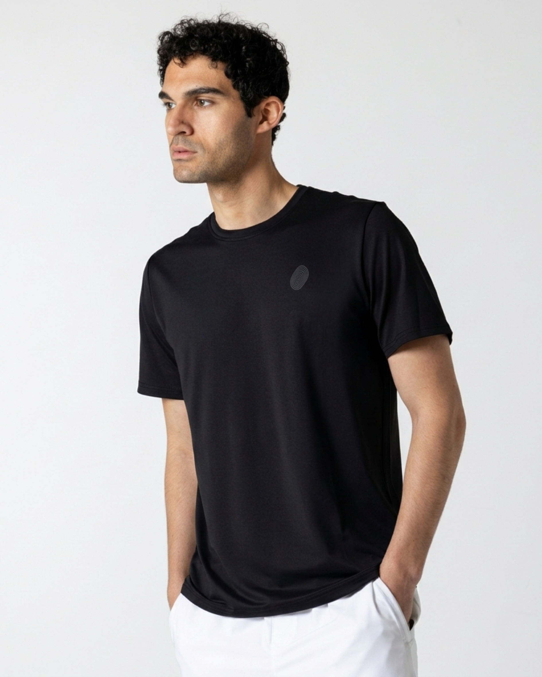 Man wearing a black t-shirt with a small logo on a light gray background