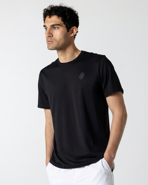 Man wearing a black t-shirt with a small logo on a light gray background