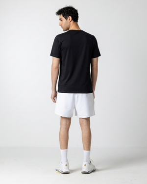 Person wearing a black t-shirt and white shorts on a plain background