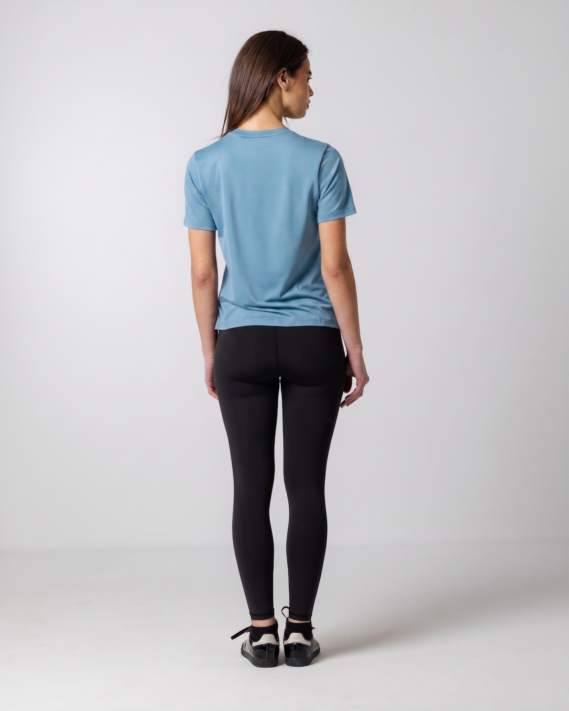 Person wearing a blue t-shirt and black leggings on a white background