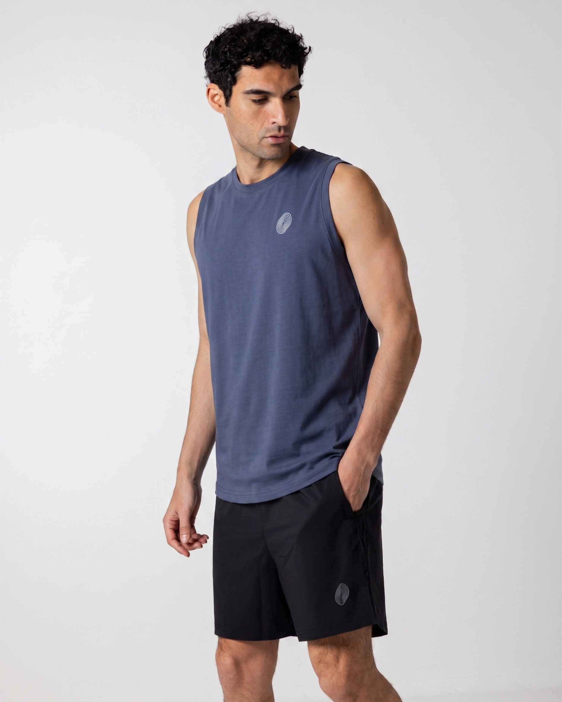 Man wearing a sleeveless navy shirt and black shorts on a white background